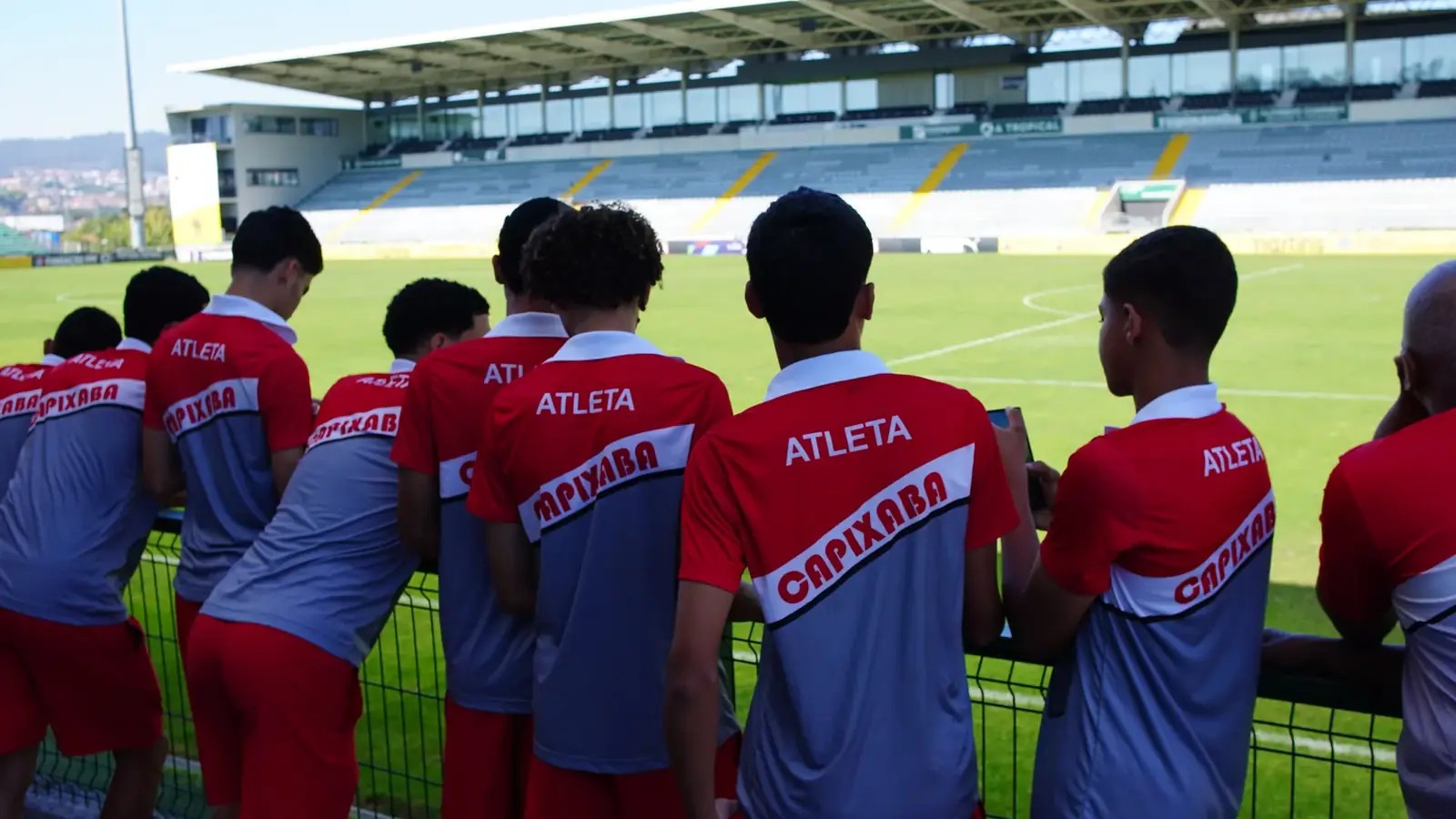 Atletas da ACF, de costas, olhando um estádio em Portugal